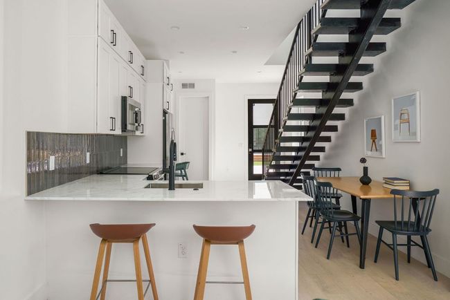 Kitchen with stainless steel microwave, a peninsula, light wood-style floors, a sink, and light stone countertops | Image 5