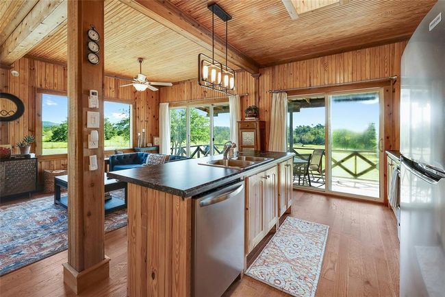 Kitchen featuring open floor plan, wood ceiling, stainless steel appliances, and a sink | Image 13