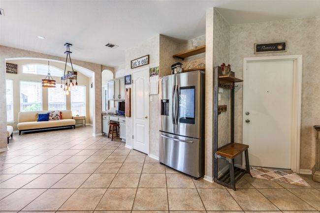 Kitchen featuring stainless steel refrigerator with ice dispenser, a chandelier, light tile patterned floors, and decorative light fixtures | Image 9