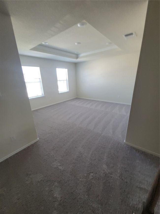 Empty room with baseboards, a tray ceiling, visible vents, and carpet | Image 16