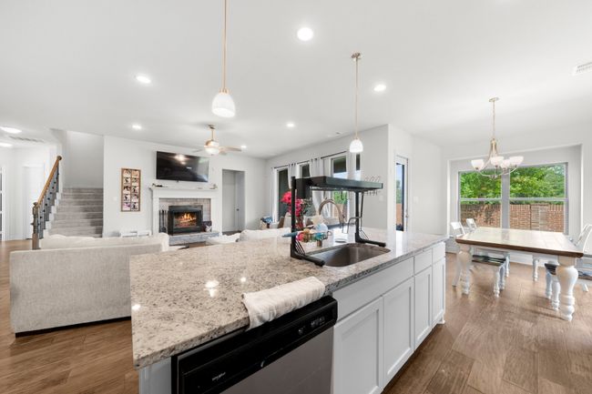 Kitchen featuring dishwasher, a fireplace, a ceiling fan, white cabinetry, and light stone counters | Image 10