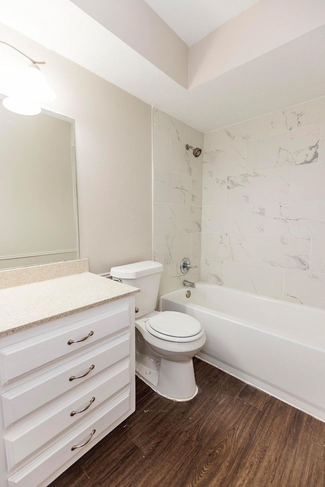 Full bathroom featuring wood finished floors, vanity, toilet, and tub / shower combination | Image 18