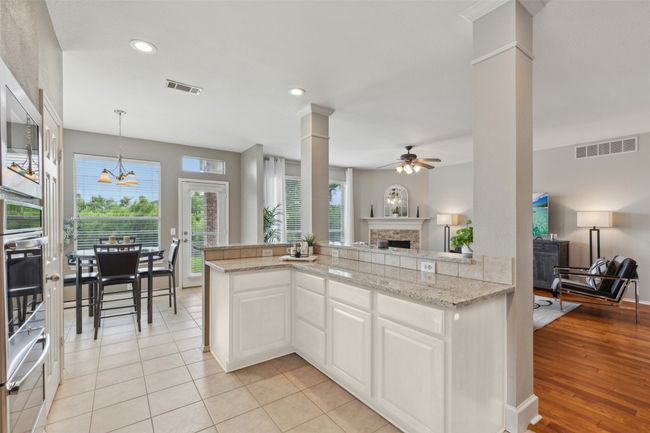 * Virtual rendering of kitchen cabinets painted white. Kitchen featuring a fireplace, open floor plan, ceiling fan, ornate columns, and hanging light fixtures | Image 6