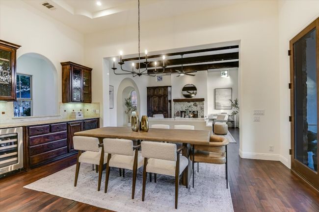 Dining area with high ceilings, mesquite wood floors, arched walkways, wine cooler, and ceiling fan with updated chandelier, and built-in buffet type bar area for additional storage | Image 13