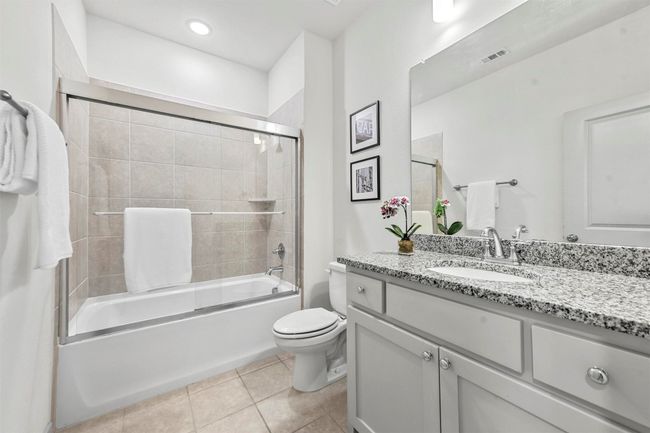 Full bathroom with tile patterned flooring, vanity, toilet, and bath / shower combo with glass door | Image 24