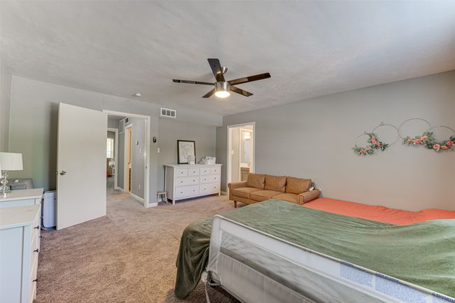Bedroom with visible vents, baseboards, ceiling fan, connected bathroom, and light carpet | Image 14