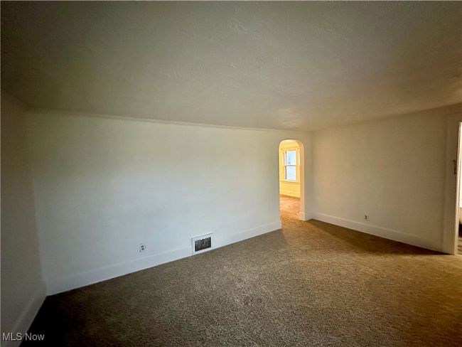 Carpeted spare room with arched walkways, visible vents, and baseboards | Image 10
