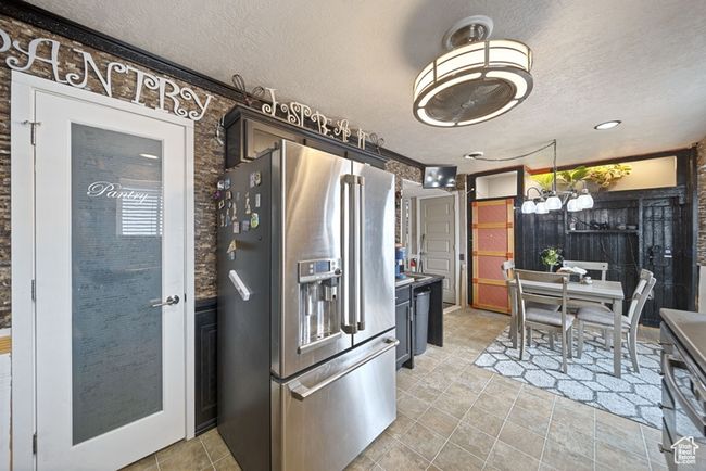 Kitchen with a chandelier, a textured ceiling, high end refrigerator, and light tile patterned floors | Image 9