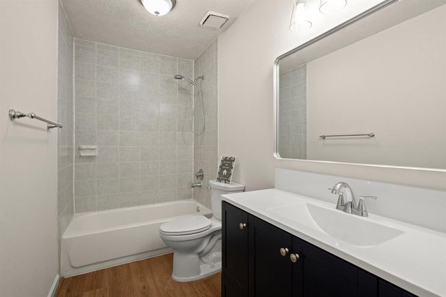 The remodeled guest bath is move-in ready with a new vanity, modern toilet, upgraded lighting, stylish flooring, and a fresh, clean aesthetic. | Image 26