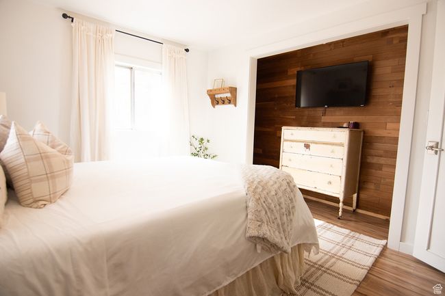 Bedroom featuring wood finished floors, wood walls, and baseboards | Image 16