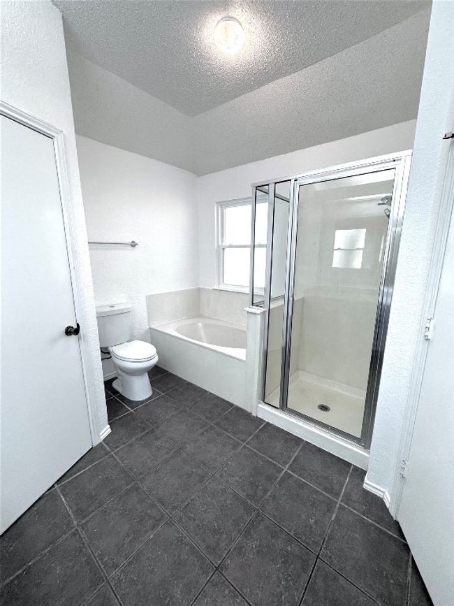 Bathroom featuring a textured ceiling, a garden tub, a stall shower, and dark tile patterned floors | Image 18