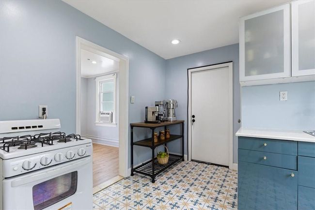 Kitchen with light tile patterned flooring, cooling unit, and white gas stove | Image 4