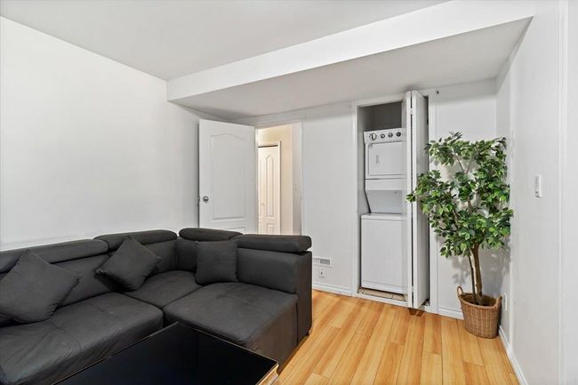 Living room featuring baseboards, light wood-style floors, and stacked washer and dryer | Image 24