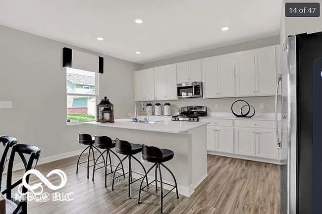 Kitchen with a kitchen breakfast bar, a sink, appliances with stainless steel finishes, and vinyl wood-type flooring | Image 5