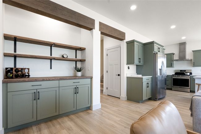 Kitchen with stainless steel appliances, wall chimney range hood, green cabinets, light wood-style flooring, and recessed lighting | Image 13