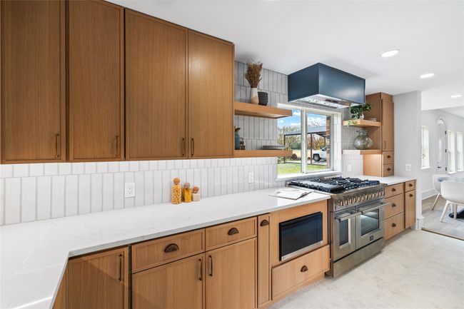 Kitchen with appliances with stainless steel finishes, open shelves, wall chimney exhaust hood, decorative backsplash, and recessed lighting | Image 13
