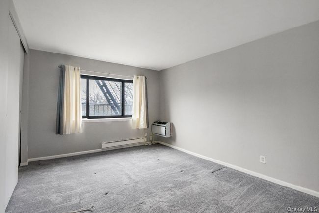 Carpeted spare room featuring baseboards, a baseboard heating unit, and a wall mounted air conditioner | Image 17