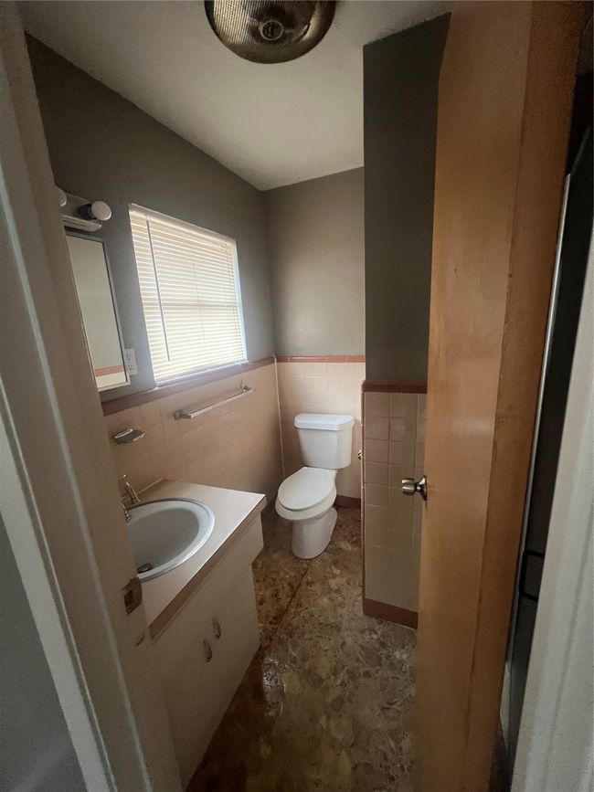 Bathroom featuring tile walls, wainscoting, toilet, and vanity | Image 11