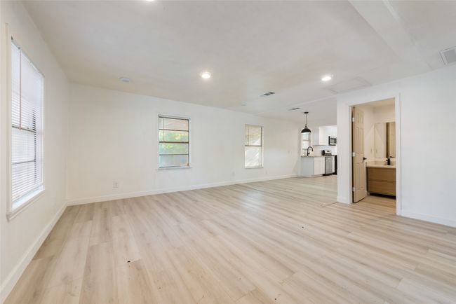 Unfurnished living room featuring attic access, light wood-type flooring, visible vents, and baseboards | Image 6