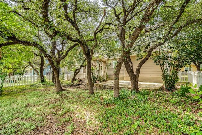 Fenced backyard area has an abundance of shade trees. | Image 23