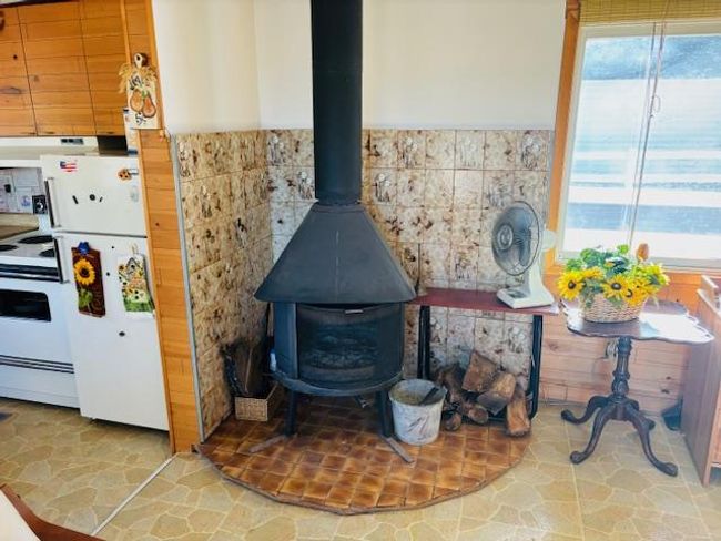 Details featuring white appliances, a wood stove, and range hood | Image 8