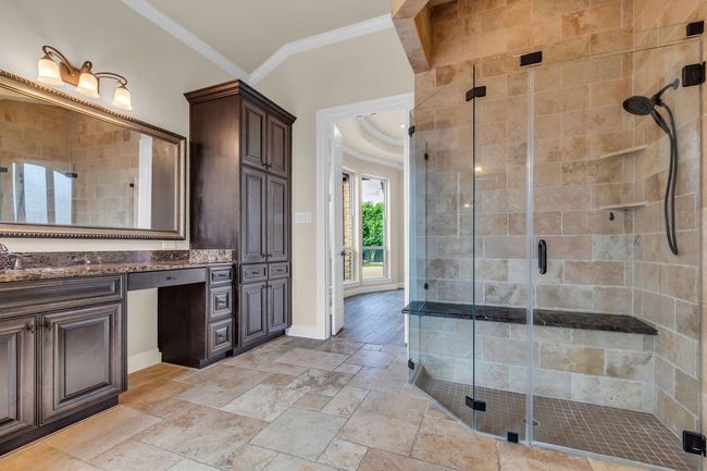 The glass-enclosed shower features a comfortable granite seat in a serene, beautifully designed space. | Image 22