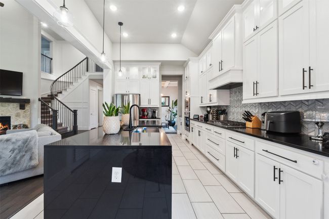 Kitchen featuring dark countertops, decorative backsplash, a stone fireplace, open floor plan, and appliances with stainless steel finishes | Image 14