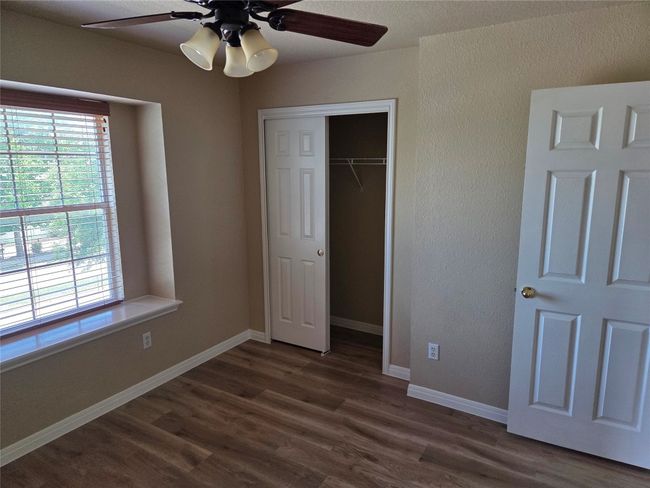 Unfurnished bedroom with multiple windows, dark wood-type flooring, a closet, ceiling fan, and a textured wall | Image 20