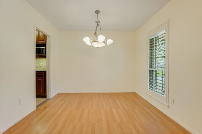 Empty room featuring light wood-style flooring, a chandelier, and baseboards | Image 8