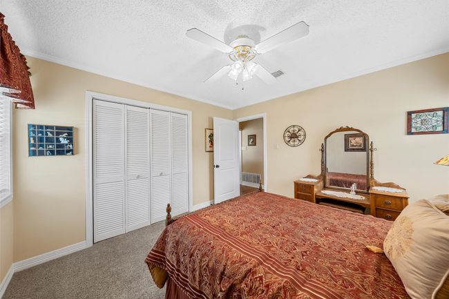 Bedroom featuring carpet floors, a closet, ornamental molding, a textured ceiling, and a ceiling fan | Image 21