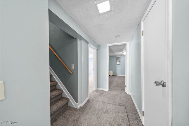Corridor to basement with light carpet and a textured ceiling | Image 26
