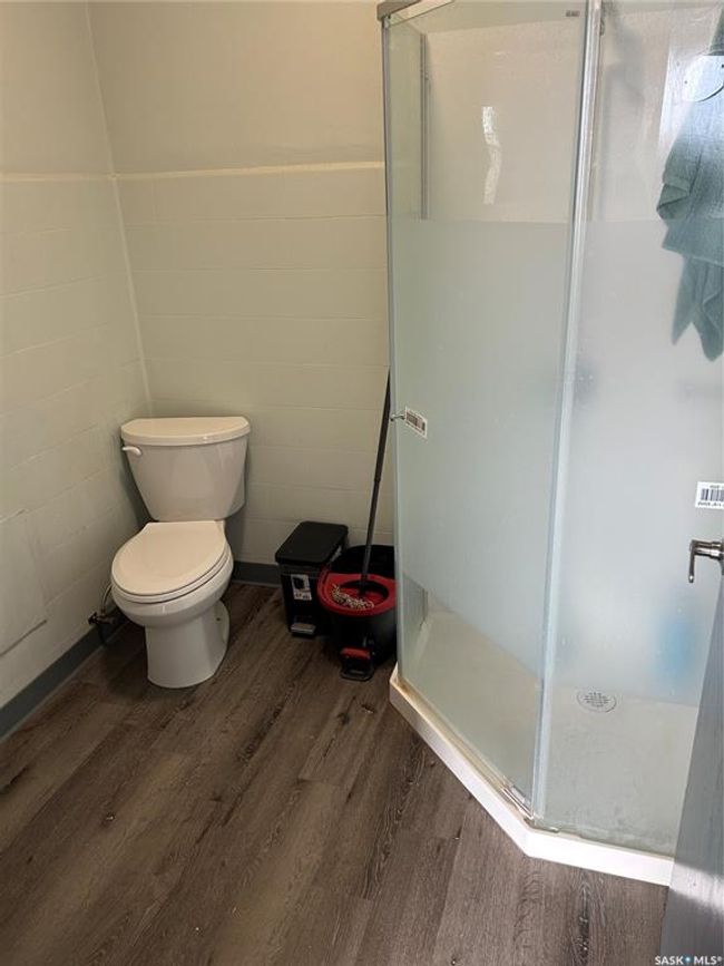Bathroom with tile walls, toilet, a stall shower, wainscoting, and wood finished floors | Image 17