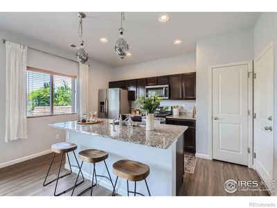 Upgraded lighting, granite island, and large pantry compliment the sunny kitchen. | Image 3