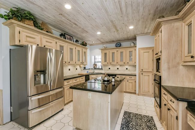 Island Kitchen boasts granite counters, matching backsplash, gorgeous cabinetry, a desk area, and ample counter space | Image 14