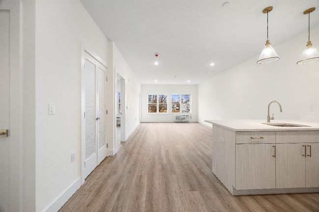 Kitchen with a sink, light wood-type flooring, light countertops, hanging light fixtures, and baseboards | Image 25