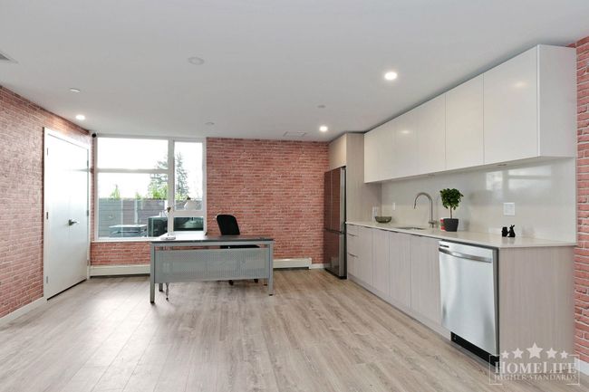 Kitchen featuring light wood-style floors, appliances with stainless steel finishes, brick wall, and a sink | Image 28