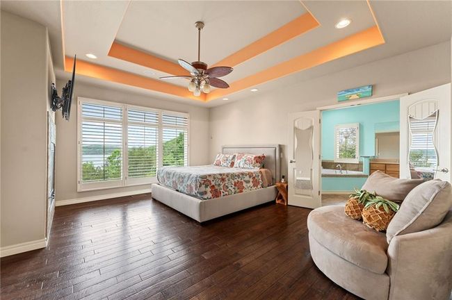 Bedroom featuring multiple windows, baseboards, a raised ceiling, and dark wood finished floors | Image 25