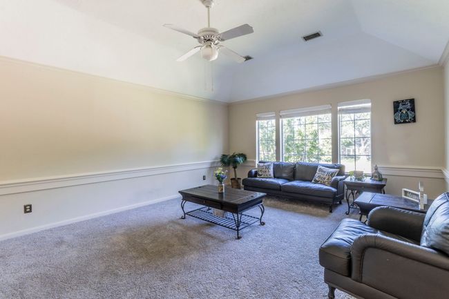 Carpeted living room featuring ceiling fan, high vaulted ceiling, and ornamental molding | Image 16