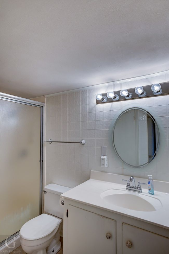 Bathroom featuring vanity, toilet, a stall shower, and tile walls | Image 15