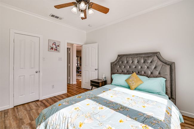 Bedroom with ceiling fan, ornamental molding, and wood-type flooring | Image 26