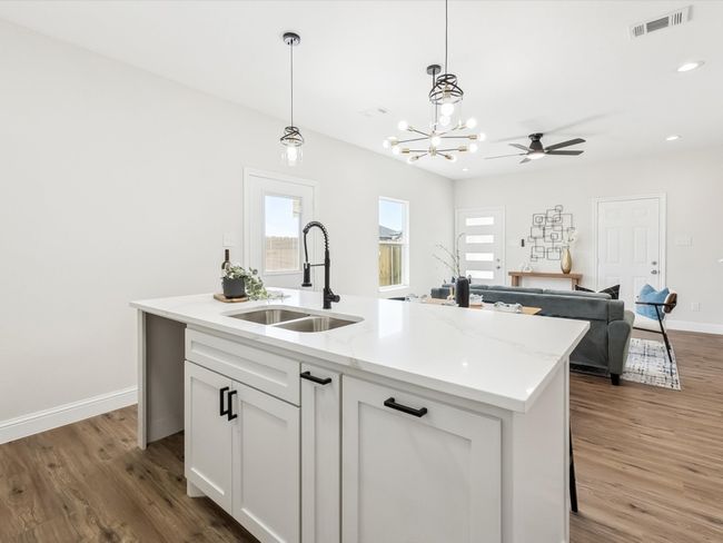 Kitchen featuring hanging light fixtures, a sink, visible vents, and light wood-style floors | Image 11