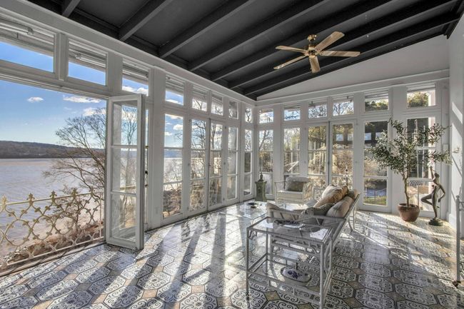 Sunroom / solarium with ceiling fan, a water view, plenty of natural light, and vaulted ceiling with beams | Image 12