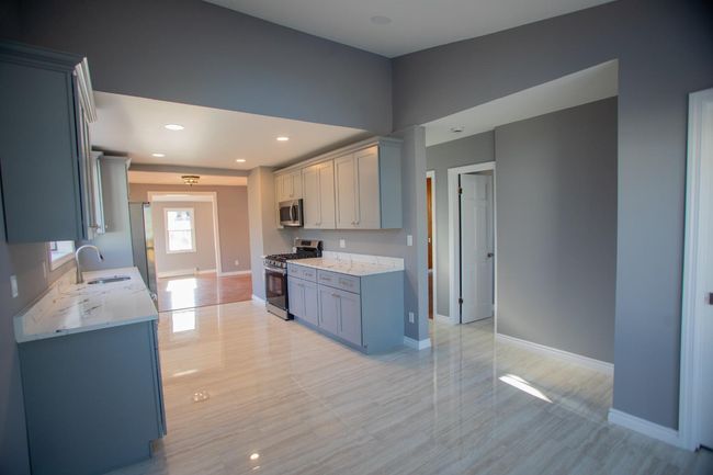 Kitchen featuring light stone countertops, sink, and appliances with stainless steel finishes | Image 12