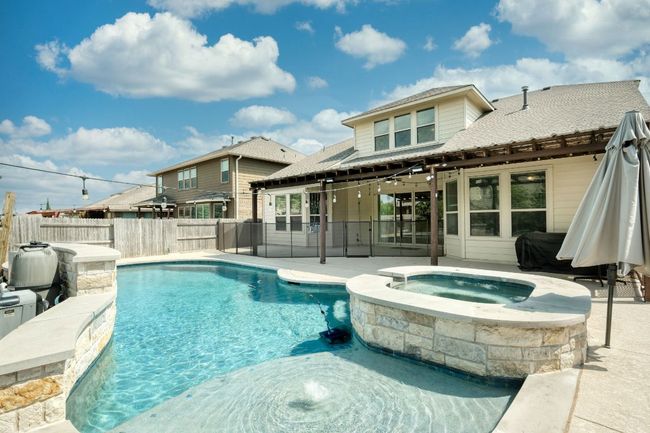View of swimming pool with a patio area, and removeable child safety fence. | Image 29