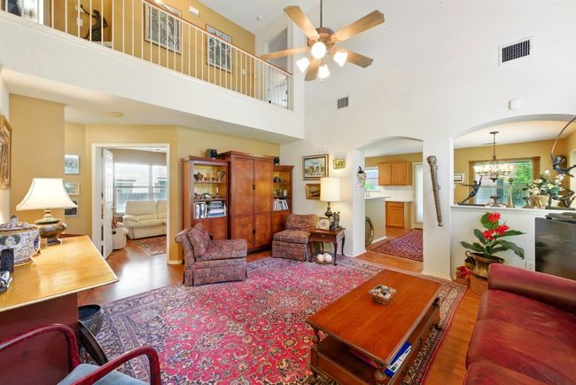 Living area with arched walkways, ceiling fan, a high ceiling, and a chandelier | Image 6