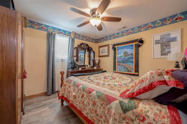 Another well-sized bedroom offers soft light through a window, with ceiling fan comfort and continued design cohesion through its wood door and consistent flooring. | Image 26