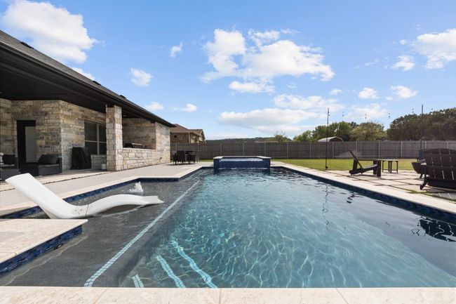 View of pool with a pool with connected hot tub, a fenced backyard, a water slide, and a patio | Image 34