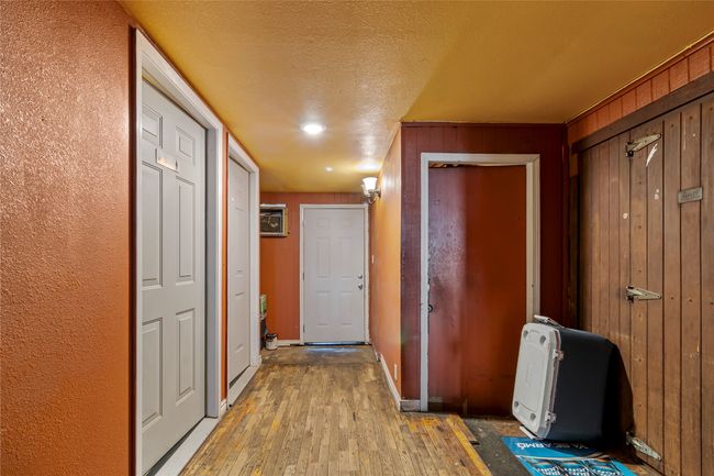 Hall featuring a textured ceiling, light hardwood / wood-style floors, and wood walls | Image 20