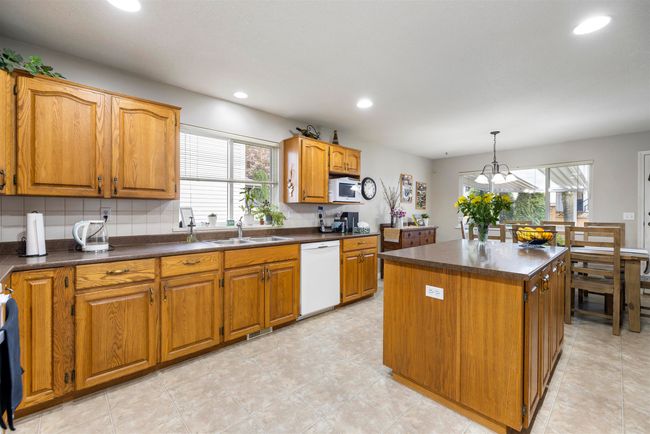 Kitchen featuring recessed lighting, dark countertops, a sink, white appliances, and a center island | Image 9