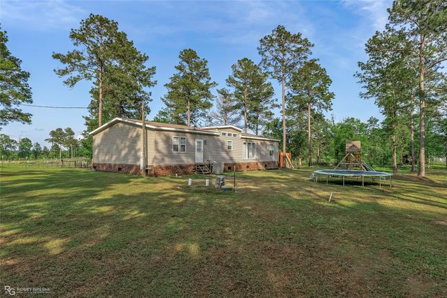 Rear view of house featuring a lawn, a trampoline, a playground, and crawl space | Image 38